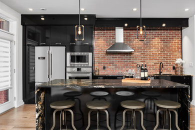 Kitchen - industrial light wood floor and brown floor kitchen idea in Toronto with an undermount sink, flat-panel cabinets, black cabinets, quartzite countertops, red backsplash, brick backsplash, stainless steel appliances and black countertops