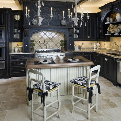 Example of a classic u-shaped travertine floor kitchen design in Dallas with paneled appliances, granite countertops, raised-panel cabinets, black cabinets and beige backsplash
