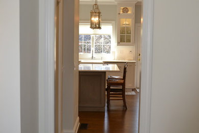 Elegant u-shaped eat-in kitchen photo in New York with a farmhouse sink and recessed-panel cabinets