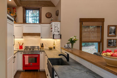 Exempel på ett mellanstort lantligt kök, med en rustik diskho, luckor med infälld panel, vita skåp, bänkskiva i täljsten, vitt stänkskydd, stänkskydd i tunnelbanekakel, integrerade vitvaror, mörkt trägolv, en halv köksö och brunt golv