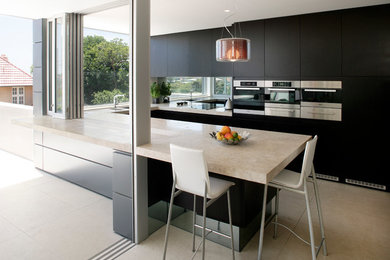 Example of a minimalist u-shaped travertine floor eat-in kitchen design in Sydney with an undermount sink, flat-panel cabinets, dark wood cabinets, marble countertops, mirror backsplash, stainless steel appliances and an island