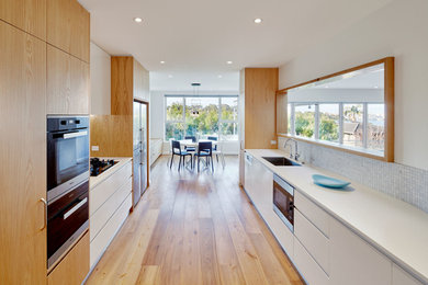 Design ideas for a modern u-shaped kitchen/diner in Sydney with stainless steel appliances and medium hardwood flooring.