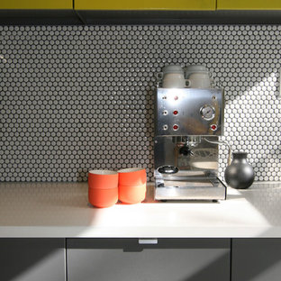 Ispirazione per una cucina minimalista di medie dimensioni con ante lisce, paraspruzzi con piastrelle in ceramica, ante gialle, top in superficie solida, paraspruzzi bianco, elettrodomestici in acciaio inossidabile, lavello sottopiano e pavimento alla veneziana