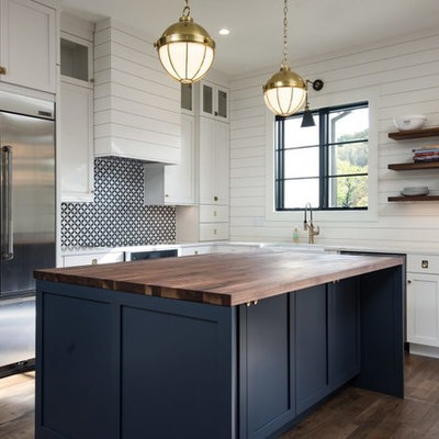 Inspiration for a mid-sized farmhouse l-shaped brown floor and dark wood floor kitchen remodel in Other with a farmhouse sink, white cabinets, stainless steel appliances, an island, shaker cabinets, wood countertops and multicolored backsplash