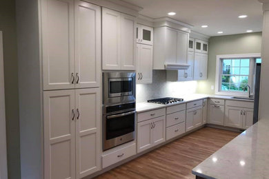 Inspiration for a large transitional l-shaped medium tone wood floor kitchen remodel in Other with an undermount sink, shaker cabinets, white cabinets, quartz countertops, stainless steel appliances, a peninsula and white countertops