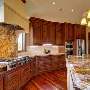 Inspiration for an expansive traditional u-shaped open plan kitchen in Denver with an undermount sink, louvered cabinets, medium wood cabinets, granite benchtops, white splashback, limestone splashback, stainless steel appliances, medium hardwood floors, with island and brown floor.