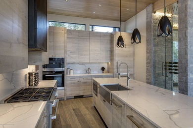 Example of a large trendy medium tone wood floor eat-in kitchen design in Denver with flat-panel cabinets, paneled appliances and an island