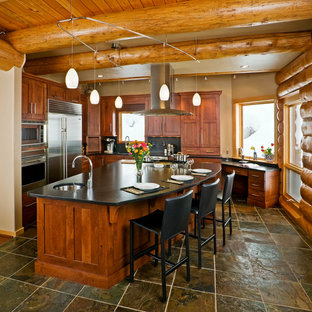 Diseño de cocina en L, rústica, con armarios estilo shaker, puertas de armario de madera oscura y electrodomésticos de acero inoxidable