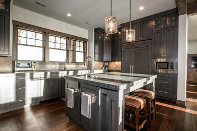 Inspiration for a large transitional u-shaped dark wood floor and brown floor open concept kitchen remodel in Other with an undermount sink, shaker cabinets, dark wood cabinets, granite countertops, gray backsplash, stone tile backsplash, paneled appliances, an island and gray countertops