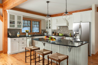 Eat-in kitchen - mid-sized rustic l-shaped medium tone wood floor eat-in kitchen idea in Burlington with white cabinets, granite countertops, multicolored backsplash, an island, an undermount sink, recessed-panel cabinets, stone tile backsplash and stainless steel appliances