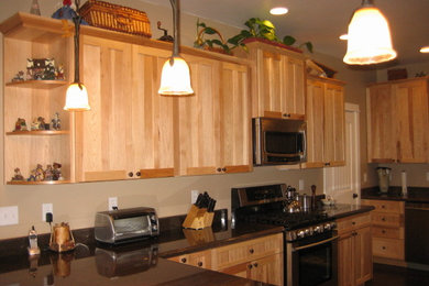 Foto de cocina tradicional de tamaño medio con armarios estilo shaker, puertas de armario de madera clara, electrodomésticos de acero inoxidable, una isla y suelo de madera oscura