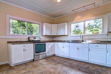 Example of a mountain style porcelain tile kitchen design in Hawaii with a double-bowl sink, white cabinets, laminate countertops and stainless steel appliances