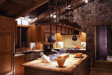 Mountain style l-shaped medium tone wood floor enclosed kitchen photo in Denver with a farmhouse sink, recessed-panel cabinets, medium tone wood cabinets, granite countertops, multicolored backsplash, stone tile backsplash, paneled appliances and an island