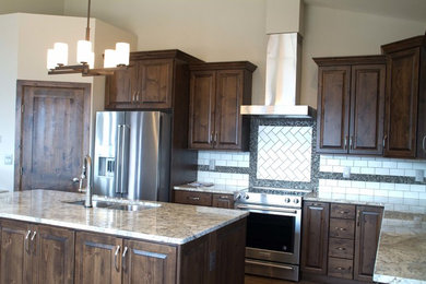 Inspiration for a mid-sized contemporary u-shaped laminate floor and brown floor open concept kitchen remodel in Denver with an undermount sink, raised-panel cabinets, brown cabinets, granite countertops, white backsplash, subway tile backsplash, stainless steel appliances and an island