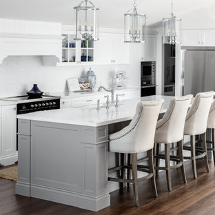 Design ideas for a large traditional l-shaped kitchen pantry in Brisbane with a farmhouse sink, shaker cabinets, white cabinets, quartz benchtops, white splashback, ceramic splashback, black appliances, dark hardwood floors, with island, brown floor, white benchtop and vaulted.
