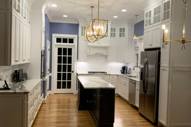 Inspiration for a mid-sized timeless l-shaped medium tone wood floor and brown floor enclosed kitchen remodel in Other with an undermount sink, recessed-panel cabinets, white cabinets, granite countertops, white backsplash, subway tile backsplash, stainless steel appliances, an island and white countertops