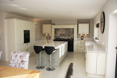 Photo of a large contemporary u-shaped open plan kitchen in Other with a built-in sink, flat-panel cabinets, white cabinets, granite worktops, integrated appliances, ceramic flooring and an island.