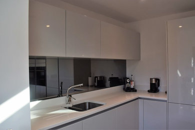 Photo of a contemporary kitchen in Other with flat-panel cabinets, grey cabinets, quartz worktops, mirror splashback, black appliances and an island.