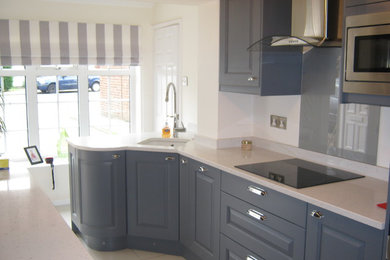 Medium sized shabby-chic style u-shaped enclosed kitchen in Other with a built-in sink, shaker cabinets, quartz worktops, grey splashback, glass sheet splashback, stainless steel appliances, porcelain flooring and a breakfast bar.
