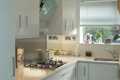 バッキンガムシャーにある小さなコンテンポラリースタイルのおしゃれな独立型キッチン (アンダーカウンターシンク、フラットパネル扉のキャビネット、白いキャビネット、珪岩カウンター、グレーのキッチンパネル、ミラータイルのキッチンパネル、パネルと同色の調理設備、クッションフロア、アイランドなし) の写真