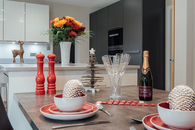 Immagine di una cucina design di medie dimensioni con ante lisce, ante grigie, elettrodomestici neri e pavimento in gres porcellanato
