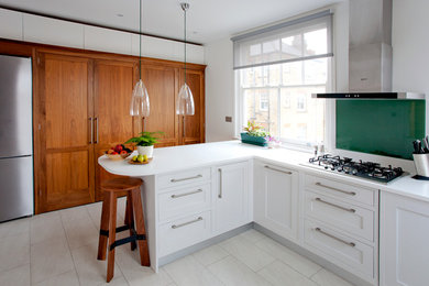 Diseño de cocinas en L actual pequeña con armarios estilo shaker, puertas de armario blancas, salpicadero gris, electrodomésticos de acero inoxidable y península