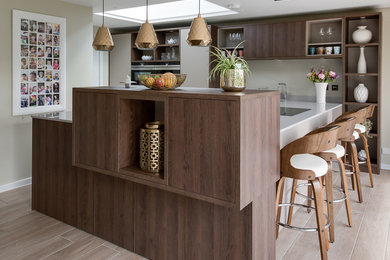 Large contemporary u-shaped kitchen/diner in Buckinghamshire with a submerged sink, flat-panel cabinets, beige cabinets, quartz worktops, integrated appliances and ceramic flooring.