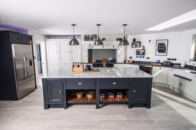 This is an example of a large traditional galley open plan kitchen in Other with a belfast sink, beaded cabinets, granite worktops, porcelain splashback, stainless steel appliances and an island.