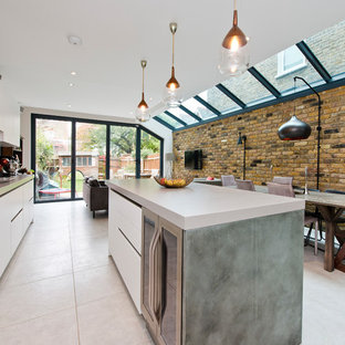 Photo of a mid-sized contemporary open plan kitchen in London with an integrated sink, flat-panel cabinets, white cabinets, solid surface benchtops, metallic splashback, with island, metal splashback and beige floor.