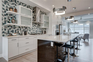 Moderne Küche mit Einbauwaschbecken, weißen Schränken, Rückwand aus Glasfliesen, Küchengeräten aus Edelstahl, hellem Holzboden, beigem Boden und weißer Arbeitsplatte in Calgary