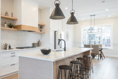 Inspiration for an industrial light wood floor and brown floor eat-in kitchen remodel in Calgary with recessed-panel cabinets, white cabinets, marble countertops, white backsplash, ceramic backsplash and white countertops