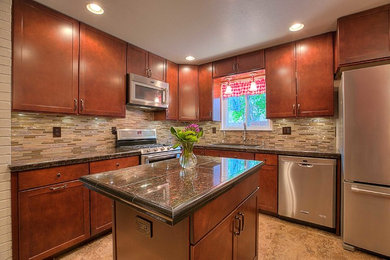 Enclosed kitchen - mid-sized transitional l-shaped medium tone wood floor enclosed kitchen idea in Albuquerque with a drop-in sink, shaker cabinets, granite countertops, multicolored backsplash, glass tile backsplash, stainless steel appliances and an island