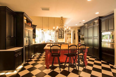 オーランドにある高級な広いトラディショナルスタイルのおしゃれなキッチン (エプロンフロントシンク、レイズドパネル扉のキャビネット、黒いキャビネット、珪岩カウンター、パネルと同色の調理設備、磁器タイルの床) の写真