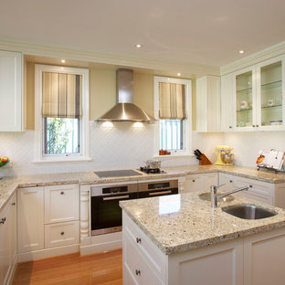 This is an example of a traditional u-shaped kitchen in Perth with an undermount sink, shaker cabinets, white cabinets, granite benchtops, white splashback, porcelain splashback, stainless steel appliances, with island, multi-coloured benchtop and medium hardwood floors.