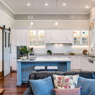 This is an example of a mid-sized transitional l-shaped open plan kitchen in Perth with an undermount sink, shaker cabinets, white cabinets, quartz benchtops, white splashback, ceramic splashback, stainless steel appliances, medium hardwood floors, brown floor, multi-coloured benchtop and multiple islands.