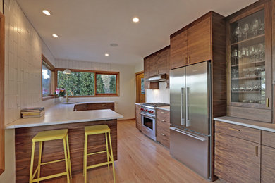Mid-sized 1950s galley medium tone wood floor and beige floor open concept kitchen photo in Portland with an undermount sink, flat-panel cabinets, dark wood cabinets, marble countertops, white backsplash, subway tile backsplash, stainless steel appliances and a peninsula