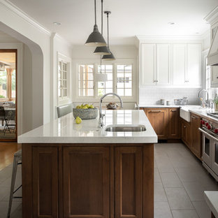 Design ideas for a large beach style u-shaped eat-in kitchen in Atlanta with a farmhouse sink, shaker cabinets, white cabinets, quartz benchtops, white splashback, subway tile splashback, panelled appliances, ceramic floors, with island, grey floor and white benchtop.