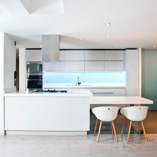 Modelo de cocina comedor en L, minimalista, de tamaño medio, con fregadero de doble seno, armarios con puertas mallorquinas, puertas de armario blancas, encimera de granito, salpicadero blanco, salpicadero de piedra caliza, electrodomésticos de acero inoxidable, suelo de cemento, una isla, suelo negro y encimeras blancas