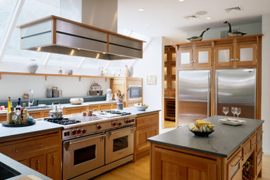 Klassische Küche mit Unterbauwaschbecken, Schrankfronten im Shaker-Stil, hellbraunen Holzschränken, Küchengeräten aus Edelstahl und braunem Holzboden in Boston