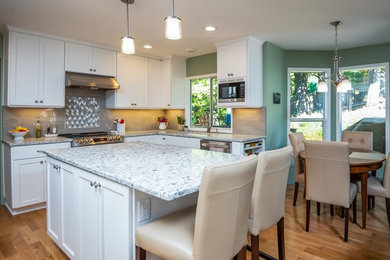 Example of a mid-sized classic l-shaped brown floor and vinyl floor eat-in kitchen design in Portland with an undermount sink, shaker cabinets, white cabinets, quartzite countertops, gray backsplash, stone tile backsplash, stainless steel appliances, an island and white countertops