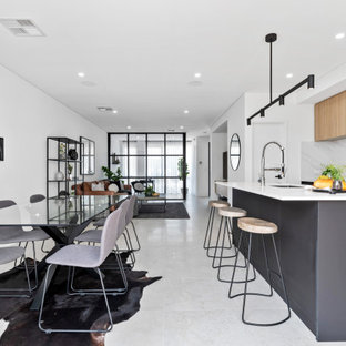 This is an example of a large scandinavian galley open plan kitchen in Perth with an undermount sink, flat-panel cabinets, black cabinets, white splashback, stainless steel appliances, with island, white floor and white benchtop.