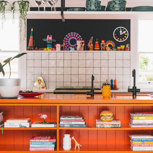 Design ideas for a contemporary kitchen in Christchurch with an undermount sink, laminate benchtops, white splashback, ceramic splashback, black appliances, painted wood floors, with island, pink floor and orange benchtop.