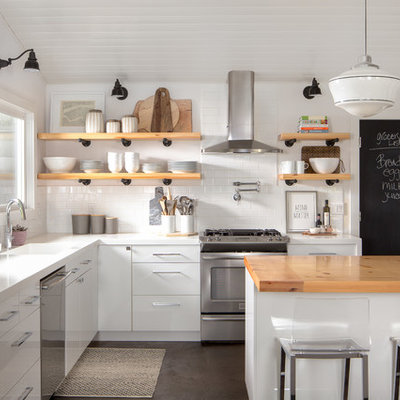 Example of a cottage l-shaped kitchen design in Sacramento with an integrated sink, flat-panel cabinets, white cabinets, wood countertops, white backsplash, subway tile backsplash, stainless steel appliances and an island