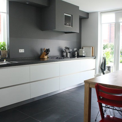 Example of a trendy kitchen design in Amsterdam with flat-panel cabinets, white cabinets and gray backsplash