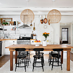 Immagine di una cucina shabby-chic style con lavello stile country, ante con riquadro incassato, ante bianche, top in legno, paraspruzzi bianco, elettrodomestici in acciaio inossidabile e parquet scuro