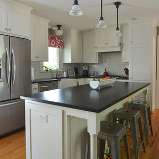 Inspiration for a timeless l-shaped eat-in kitchen remodel in Dallas with shaker cabinets, stainless steel appliances, a farmhouse sink, white cabinets, white backsplash and subway tile backsplash