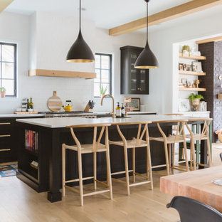 Scandinavian open concept kitchen ideas - Open concept kitchen - scandinavian light wood floor and exposed beam open concept kitchen idea in Chicago with black cabinets, white backsplash, subway tile backsplash, an island, white countertops and shaker cabinets