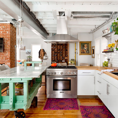 Open concept kitchen - eclectic l-shaped medium tone wood floor open concept kitchen idea in Providence with a triple-bowl sink, flat-panel cabinets, white cabinets, wood countertops, white backsplash, subway tile backsplash, stainless steel appliances and an island