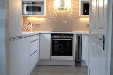 This is an example of a small contemporary u-shaped enclosed kitchen in Other with a double-bowl sink, flat-panel cabinets, white cabinets, soapstone worktops, beige splashback, porcelain splashback, coloured appliances, porcelain flooring and no island.
