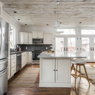 Photo of a mid-sized transitional l-shaped eat-in kitchen in Indianapolis with recessed-panel cabinets, stainless steel appliances, with island, brown floor, an undermount sink, white cabinets, granite benchtops, black splashback, slate splashback, medium hardwood floors and black benchtop.